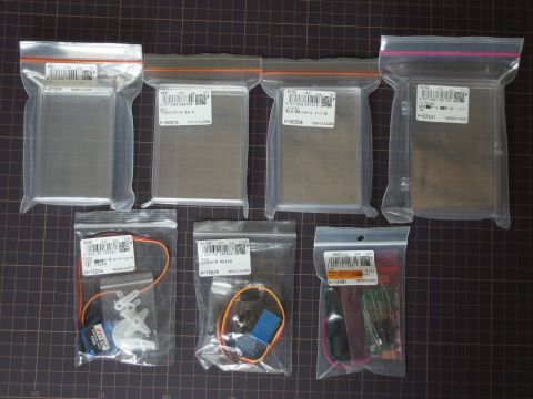 秋月電子通商で買ったモノ一覧。上段は電子工作に使う透明プラスチックケース（大きさ別4種類）、下段の左から、連続回転サーボ、マイクロサーボ、LED点滅キットです。何か工作するときのストックとしていろいろ買ってみました。